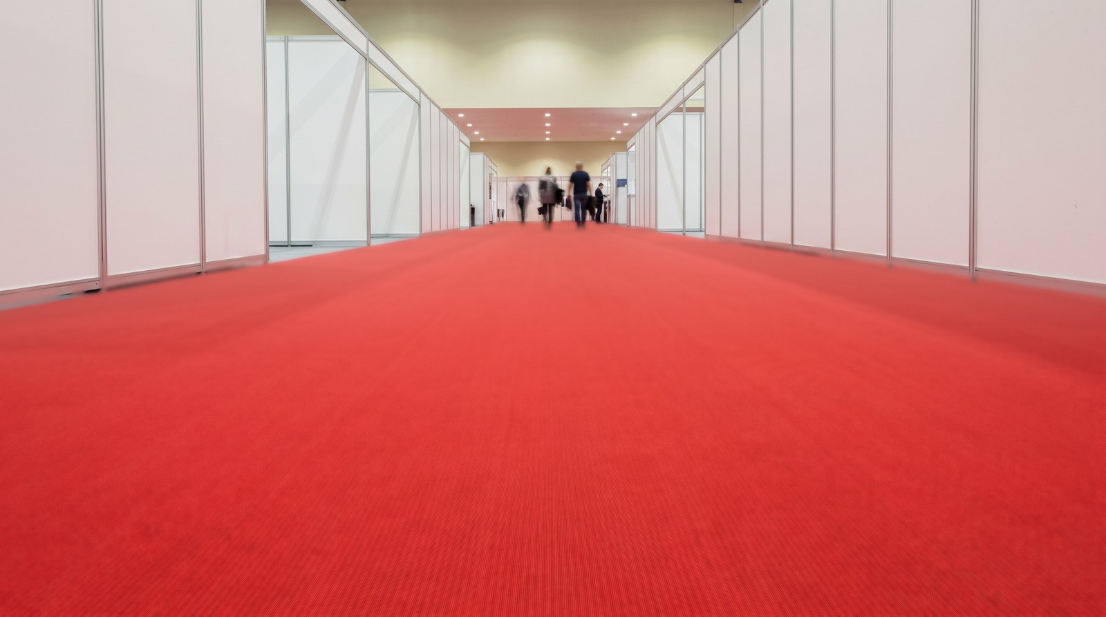 Red ribbed event carpet running down a trade show aisle between white booths