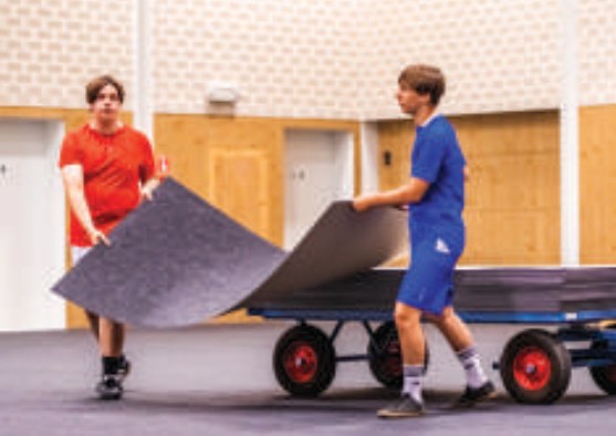 Gym floor cover tile rolling off a storage cart onto a school gym floor